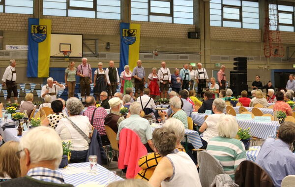 Senior*innen sitzen an Tischen bei der Großveranstaltung im Rahmen der Woche 55+