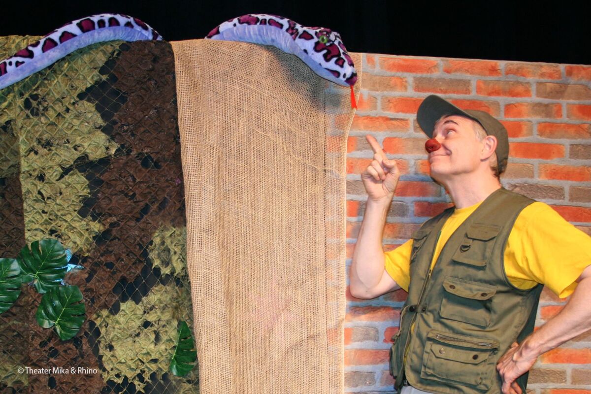 Schauspiel: Ein Tierpfleger mit roter Nase zeigt auf eine Schlange aus Stoff