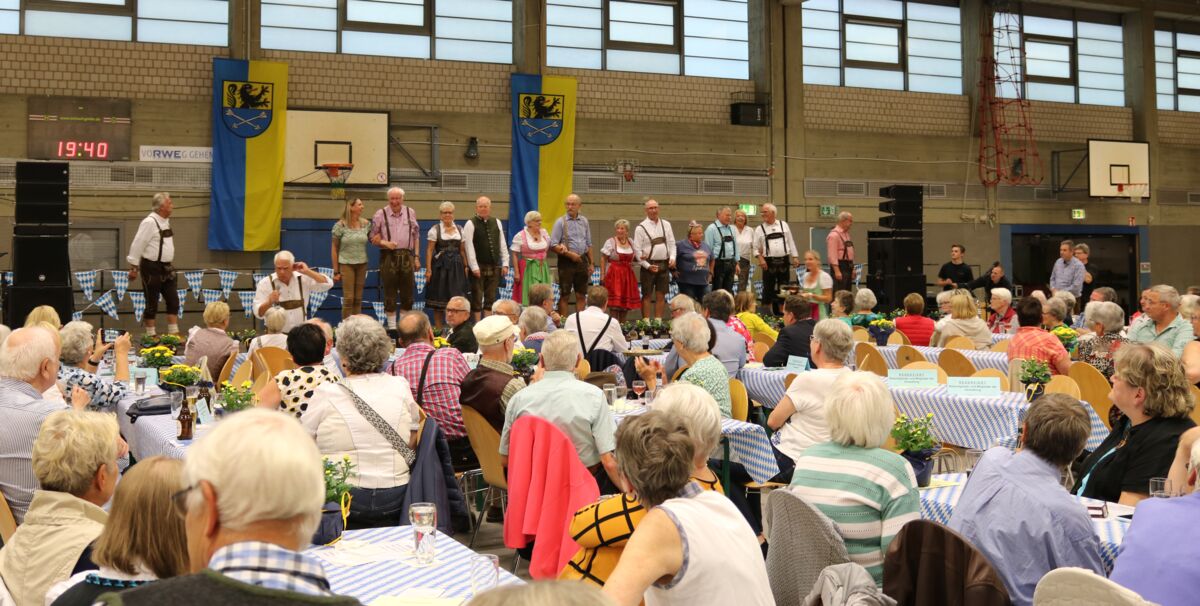 Senior*innen sitzen an Tischen bei der Großveranstaltung im Rahmen der Woche 55+