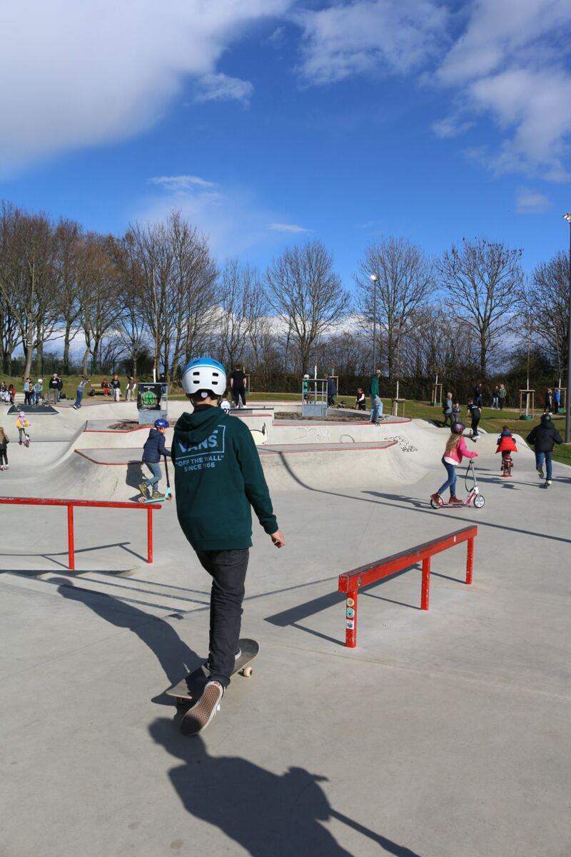 Jugendliche fahren auf dem Skate-Platz im Sport- und Bürgerpark mit ihren Boards und Rollern.